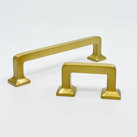 Two gold cabinet handles on a white background